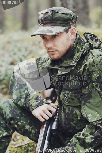 Image of young soldier or hunter with gun in forest