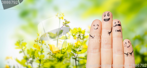 Image of close up of fingers with smiley faces over nature