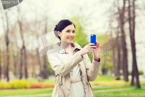 Image of smiling woman taking picture with smartphone