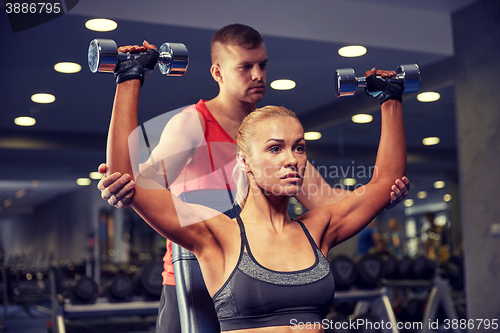 Image of man and woman with dumbbells in gym