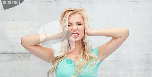 Image of young woman holding to her head and screaming