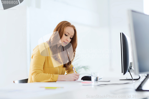 Image of creative female office worker writing to notebook