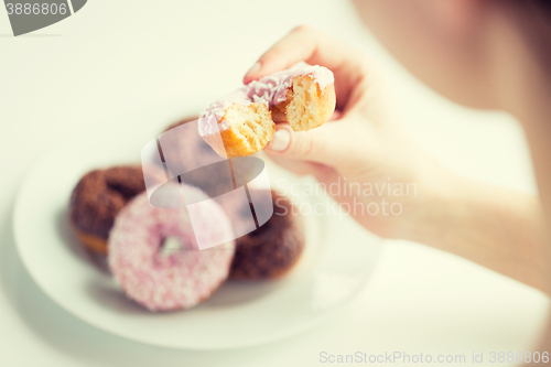 Image of close up of hand holding bitten glazed donut