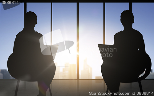 Image of silhouette of two business women with laptop