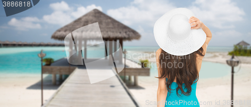 Image of woman in swimsuit and sun hat from back on beach
