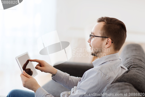 Image of smiling man working with tablet pc at home