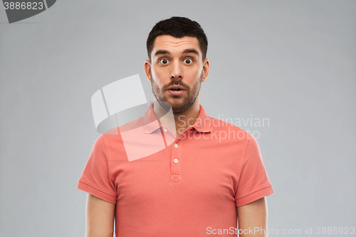 Image of surprised man in polo t-shirt over gray background