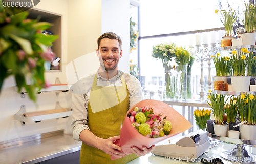 Image of smiling florist man making bunch at flower shop