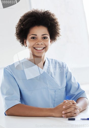 Image of happy doctor or nurse with clipboard at hospital