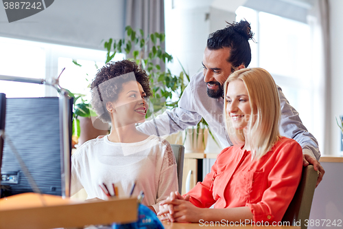 Image of happy creative team with computer in office