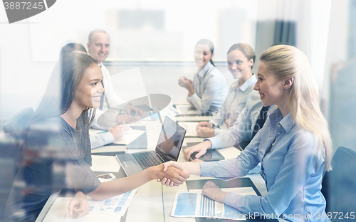 Image of smiling business people shaking hands in office