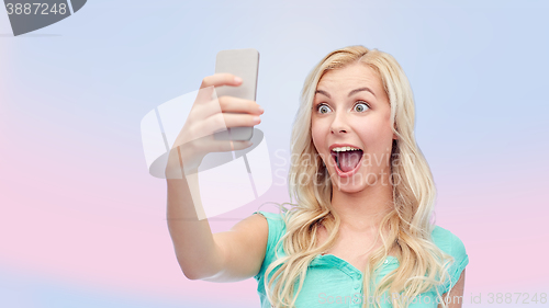 Image of smiling young woman taking selfie with smartphone