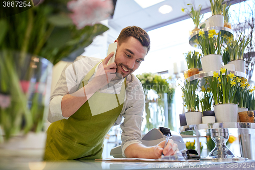 Image of man with smartphone making notes at flower shop