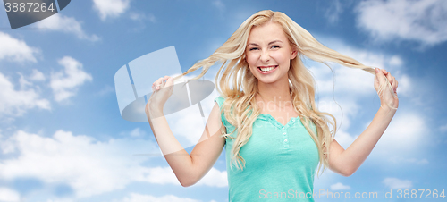 Image of smiling young woman holding strands of her hair