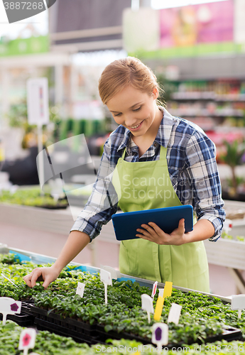 Image of happy woman with tablet pc in greenhouse