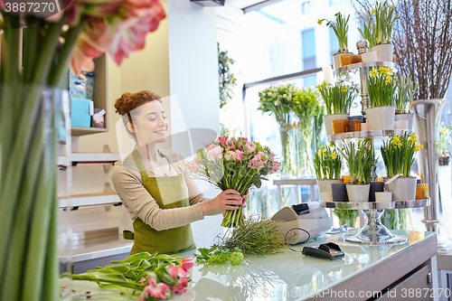 Image of smiling florist woman making bunch at flower shop