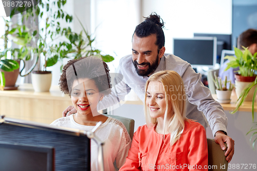 Image of happy creative team with computer in office