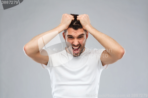 Image of crazy shouting man in t-shirt over gray background