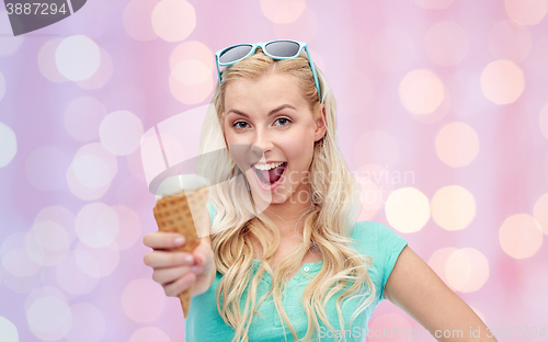 Image of happy young woman in sunglasses eating ice cream