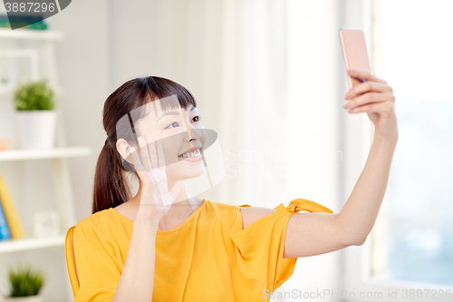 Image of happy asian woman taking selfie with smartphone