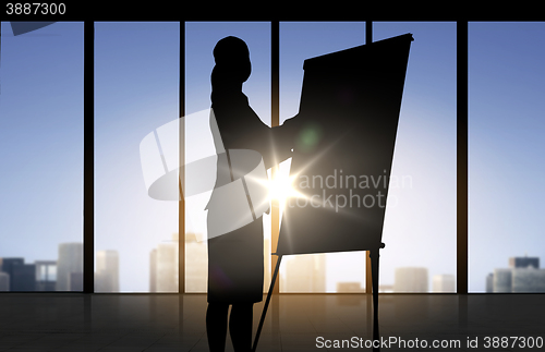 Image of silhouette of woman with flipboard over office