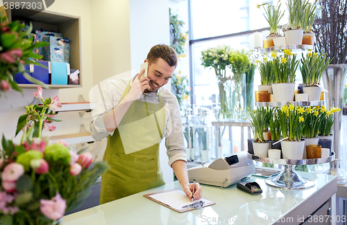 Image of man with smartphone making notes at flower shop