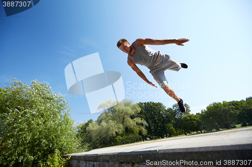 Image of sporty young man jumping in summer park