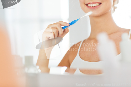 Image of woman with toothbrush cleaning teeth at bathroom