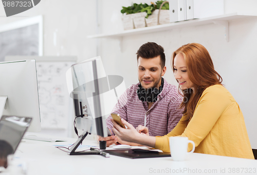 Image of smiling creative team with smartphones at office