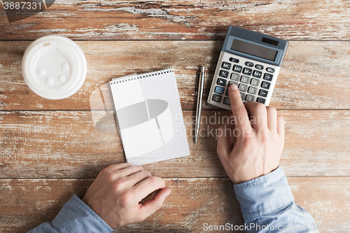 Image of close up of hands with calculator and notebook