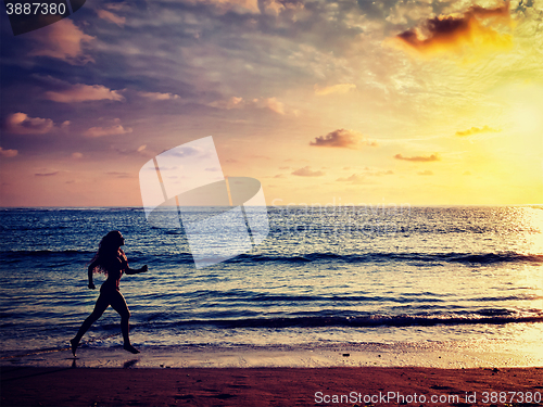 Image of Beautiful athletic woman running along sea on the beach