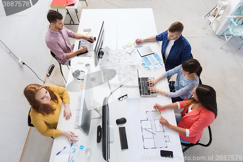 Image of creative team with computers, blueprint at office