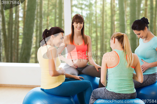 Image of happy pregnant women sitting on balls in gym