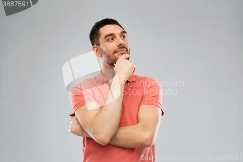 Image of man in polo t-shirt thinking over gray background