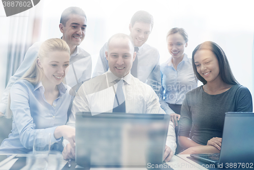 Image of smiling business people with laptop in office