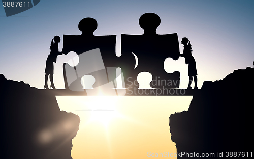 Image of silhouette of two business women connecting puzzle