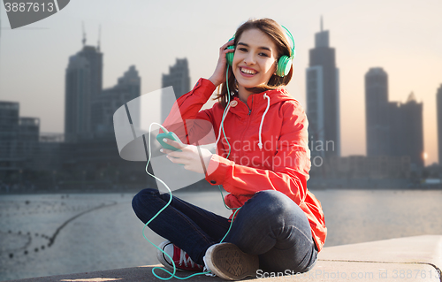 Image of happy young woman with smartphone and headphones