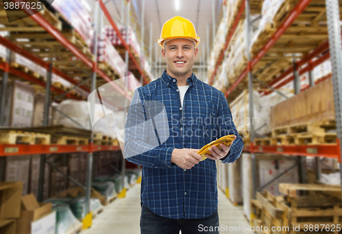 Image of happy man in hardhat with gloves over warehouse