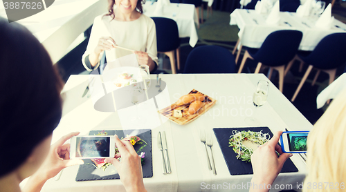 Image of close up of women picturing food by smartphones