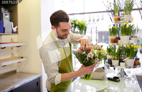 Image of smiling florist man making bunch at flower shop