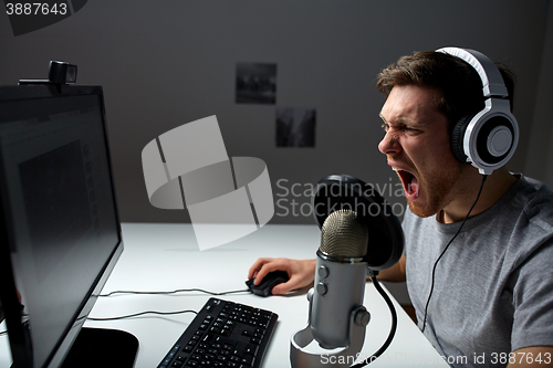 Image of man in headset playing computer video game at home