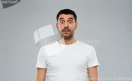 Image of scared man in white t-shirt over gray background