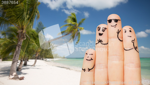 Image of close up of fingers with smiley faces on beach