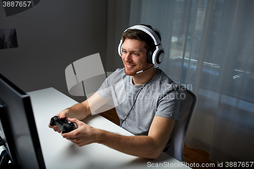 Image of man in headset playing computer video game at home