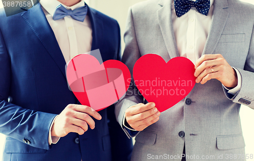 Image of close up of male gay couple holding red hearts