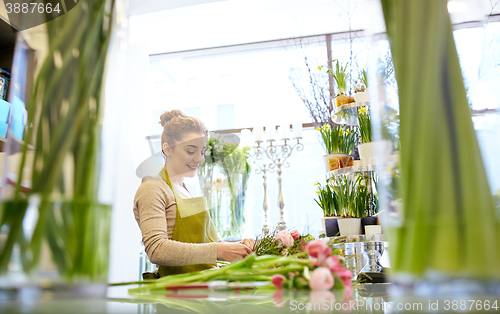 Image of smiling florist woman making bunch at flower shop