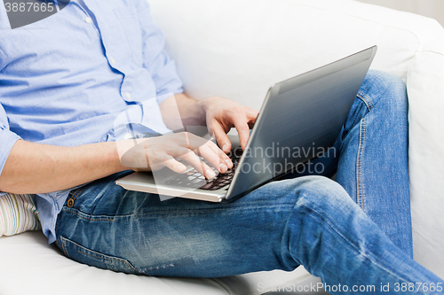 Image of close up of man typing on laptop computer at home