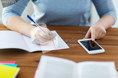 Image of close up of student with smartphone and notebook