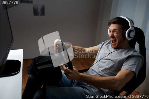 Image of man playing car racing video game at home