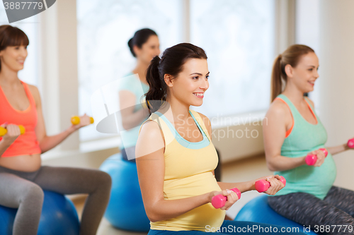 Image of happy pregnant women exercising on fitball in gym